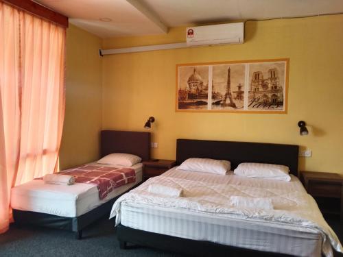 a bedroom with two beds and a picture on the wall at Putat Gajah Villa PASIR MAS in Pasir Mas