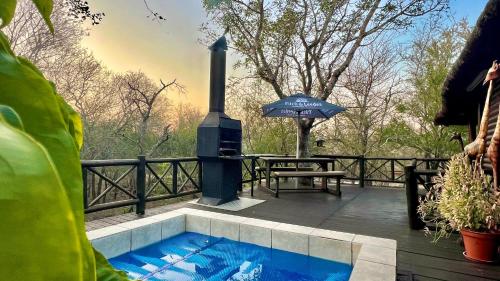 eine Terrasse mit einem Whirlpool und einem Sonnenschirm in der Unterkunft Kruger Kumba - Lahlekile Nathi in Marloth Park