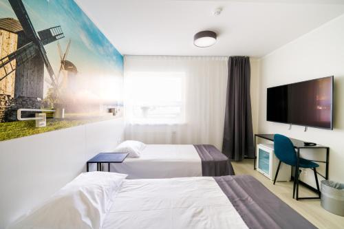 a hotel room with two beds and a flat screen tv at Hotel NOSPA in Kuressaare