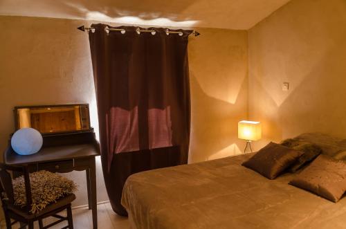 a bedroom with a bed and a desk and a window at L'Oustaou des Monges in Mollans-sur-Ouvèze