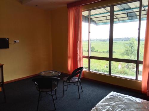 a room with a table and chairs and a large window at Putat Gajah Villa PASIR MAS in Pasir Mas