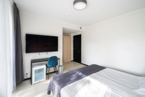 a bedroom with a bed and a tv and a chair at Hotel NOSPA in Kuressaare