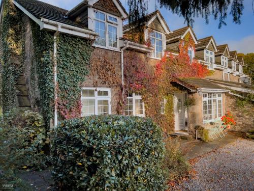a house covered in ivy with a bush in front of it at Wye Valley near Tintern Abbey Charming cottage within farmhouse Rocklea Farm,Broadstone, Trellech Monmouthshire in Monmouth