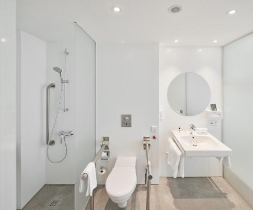 a white bathroom with a toilet and a sink at Holiday Inn Vilnius by IHG in Vilnius
