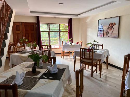 un comedor con mesas y sillas y una ventana en Lavender Garden Hotel, en Tsavo
