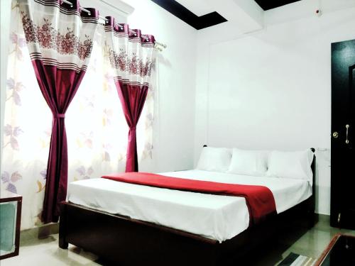 a bedroom with a bed with red and white curtains at Continental Homestay in Port Blair