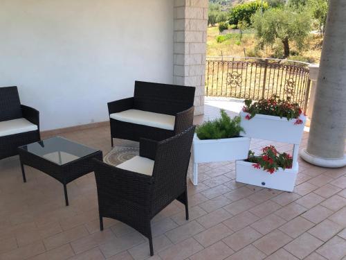 a patio with chairs and tables and potted plants at B&B Rosa dei Venti in Roseto Capo Spulico