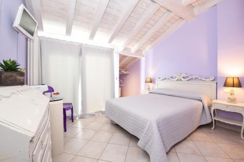 a white bedroom with a white bed and a table at Le Rêve - Lake view rooms in Sirmione
