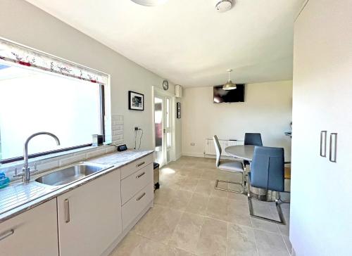 a kitchen with a sink and a table with chairs at The Nook Oranmore Holiday Home by Trident Holiday Homes in Oranmore