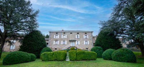 a large brick building with bushes in front of it at Manoir majestueux à Satillieu avec piscine privée in Satillieu
