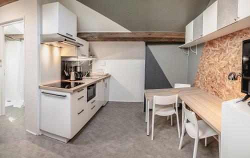 une cuisine avec des armoires blanches et une table en bois dans l'établissement Studio à 10min du Puy du Fou - Bords de Sèvre, à Saint-Laurent-sur-Sèvre