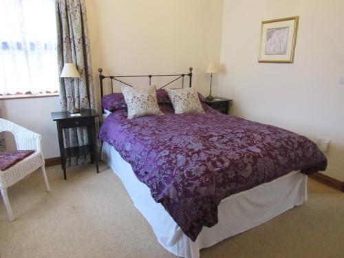 a bedroom with a bed with a purple comforter at Sunny Hill in Penrith