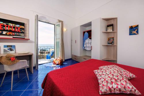 a bedroom with a red bed and a desk and a window at Maison Escher in Atrani