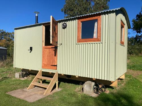 a green tiny house with a wooden door and a ramp at The Dragon's Hut with cozy logburner in Wrexham