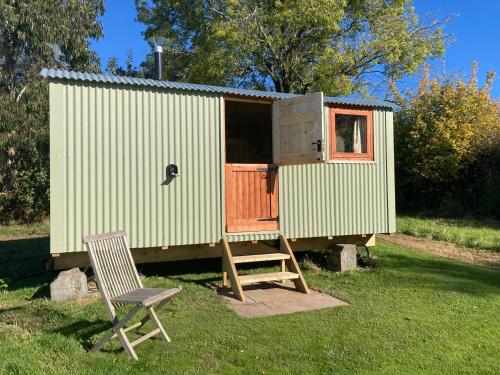 a green shed with a chair and a ladder and a chair sidx sidx sidxpite at The Dragon's Hut with cozy logburner in Wrexham