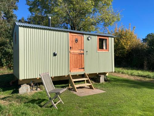 a tiny house with a wooden door and a chair at The Dragon's Hut with cozy logburner in Wrexham