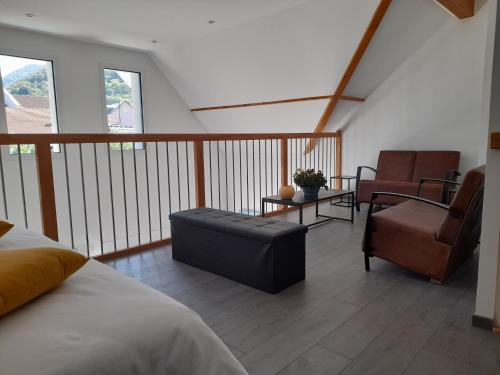 a bedroom with a balcony with a bed and a chair at Gîte les gentianes Fleurs des Pyrénées in Argelès-Gazost