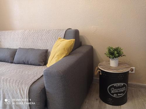 un sofá gris con una almohada amarilla junto a una mesa en studio climatisé, 50 m de la prom, Wifi, en Niza