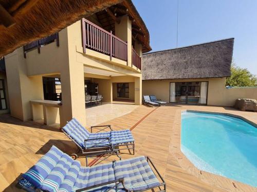 une terrasse avec des chaises longues et une piscine dans l'établissement Moshate Lodge Zebula 4 Bedroom Holiday home, à Mabula