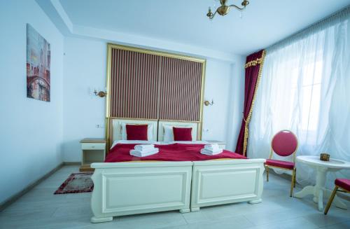 a bedroom with a white bed with red sheets at Vila Bohemia in Sibiu