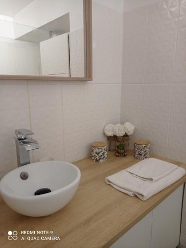 une salle de bain avec un lavabo blanc sur un comptoir en bois dans l'établissement studio climatisé, 50 m de la prom, Wifi, à Nice