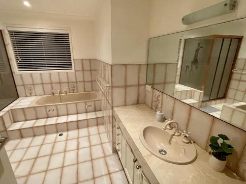 a bathroom with a sink and a tub and a mirror at Spacious 4BR getaway with panoramic water & mountain view in Green Point