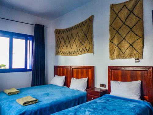 two beds in a room with blue sheets at Dar Iziki in Sidi Kaouki