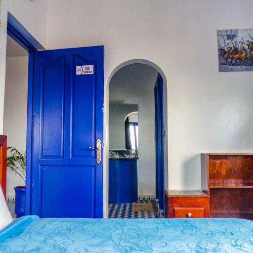 a blue door leading to a bedroom with a bed at Dar Iziki in Sidi Kaouki