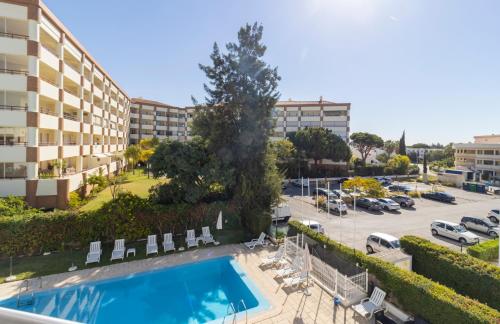 an apartment with a swimming pool and a parking lot at ZARCO - Apartment in Vilamoura with 2 Pools near the Beach & the Marina in Quarteira