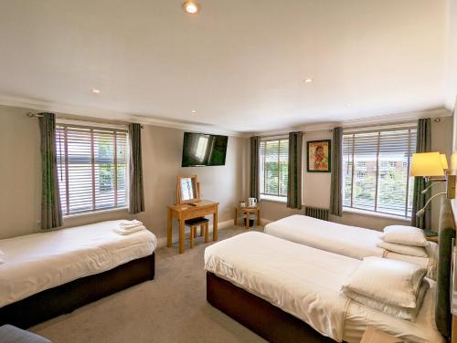 a bedroom with two beds and a desk and windows at Hotel Celebrity in Bournemouth