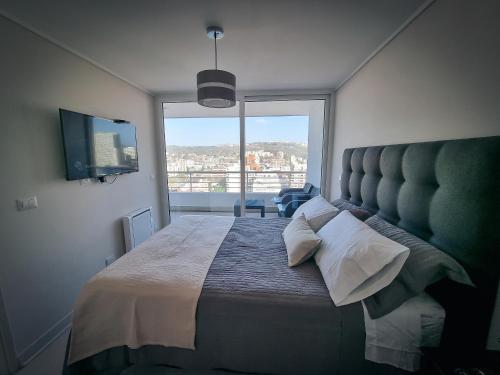 a bedroom with a large bed with a large window at Exclusivo Departamento a Pasos de la Playa en Viña in Viña del Mar