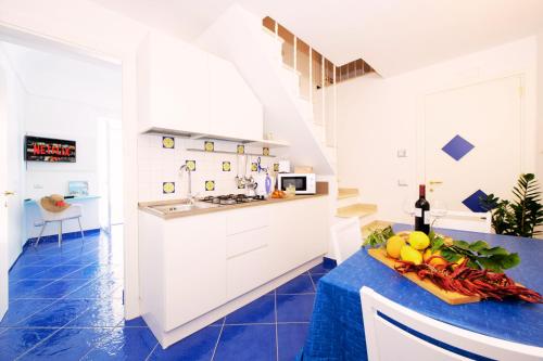 a kitchen with white cabinets and a blue floor at Maison Escher in Atrani