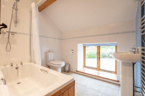 uma casa de banho com uma banheira, um WC e um lavatório. em The Stables em Bromyard