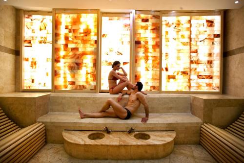 two people sitting on a tub in a bathroom at A Hoteli - Hotel Izvor in Arandjelovac