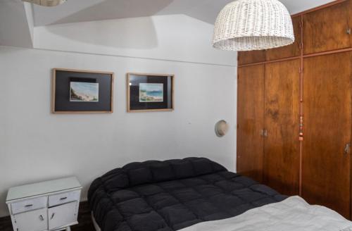 a bedroom with a black bed and a chandelier at Preciosa casa familiar - Piscina UBICACION GENIAL in Mendoza