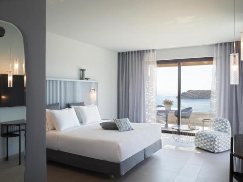a hotel room with a bed and a dining room at Cayo Exclusive Resort & Spa in Elounda