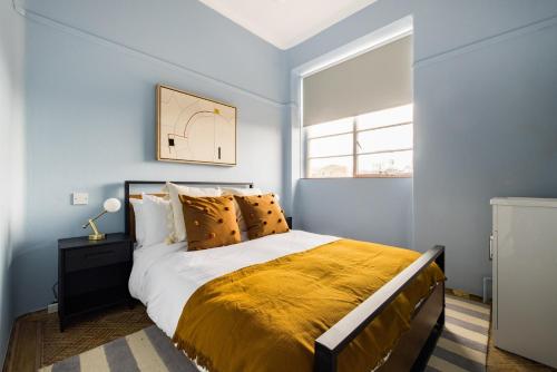 a blue bedroom with a bed with a yellow blanket at The West End Penthouse - 4BDR with Views in London