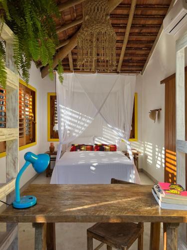 a bedroom with a bed and a wooden table at VILA IJEXÁ casas e bangalôs CARAÍVA BA in Caraíva