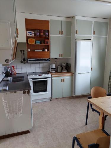 Nederhögen Vildmarkscenter appartement في Rätan: مطبخ فيه دواليب بيضاء وثلاجة بيضاء