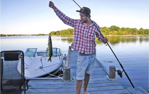 a man is standing on a dock with a boat at 3 Bedroom Lovely Home In Ronneby in Ronneby