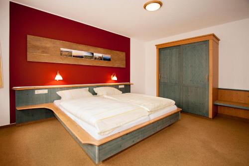 ein Schlafzimmer mit einem großen Bett mit einer roten Wand in der Unterkunft Hotel Gut Vorwald in Schmallenberg