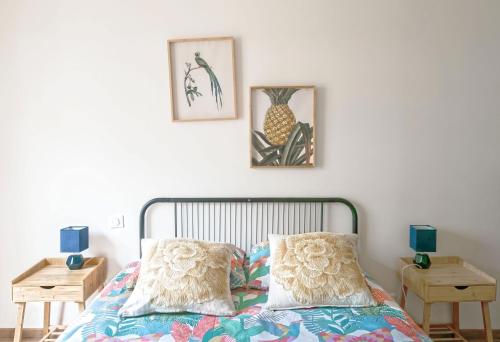 a bedroom with a bed with two tables and two pictures on the wall at Résidence Epinat - Appartements centre & parking in Vichy