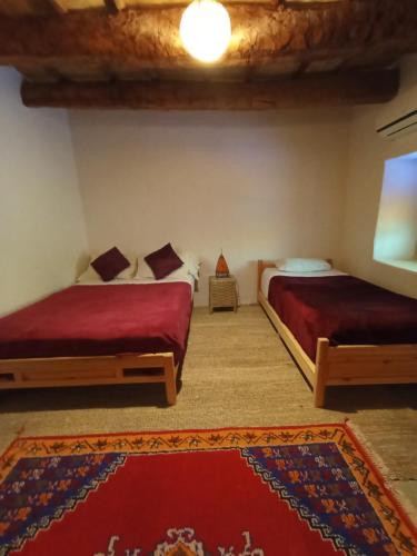 a bedroom with two beds and a rug at Auberge Bassou in Nkob