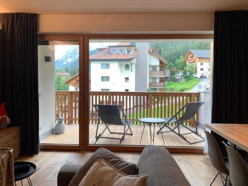 ein Wohnzimmer mit einem Balkon mit einem Tisch und Stühlen in der Unterkunft Ciasa Ciaccio in St. Vigil