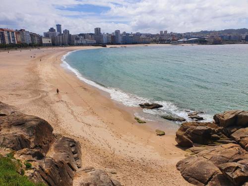 a beach with rocks and the ocean and a city at Habitación Doble Particular in A Coruña