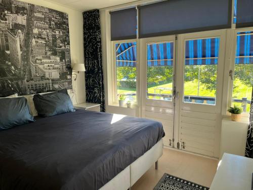 una camera con un grande letto e finestre di B&B de Zandtaart a Egmond aan Zee