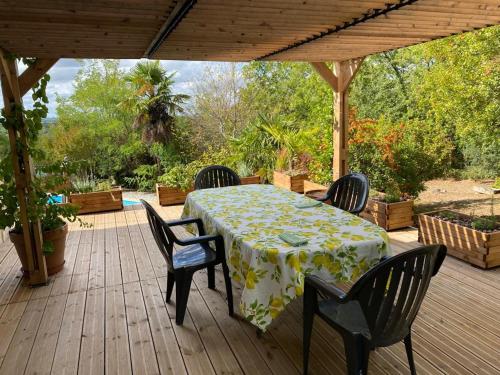 een tafel en vier stoelen op een houten terras bij Maison de 2 chambres avec piscine privee jardin amenage et wifi a Bruniquel in Bruniquel