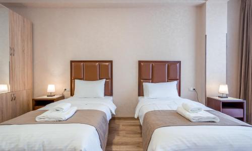 two beds in a hotel room with towels on them at Aura Hotel Tbilisi in Tbilisi City