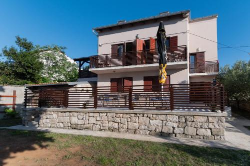 a house with a stone retaining wall and a building at Beachfront apartments Calm Sea in Preko