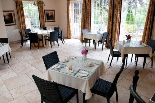 a dining room with tables and chairs and windows at Dunsley Hall Hotel in Stourbridge